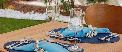 A wooden dining table set with blue napkins, silverware, and a glass of water.