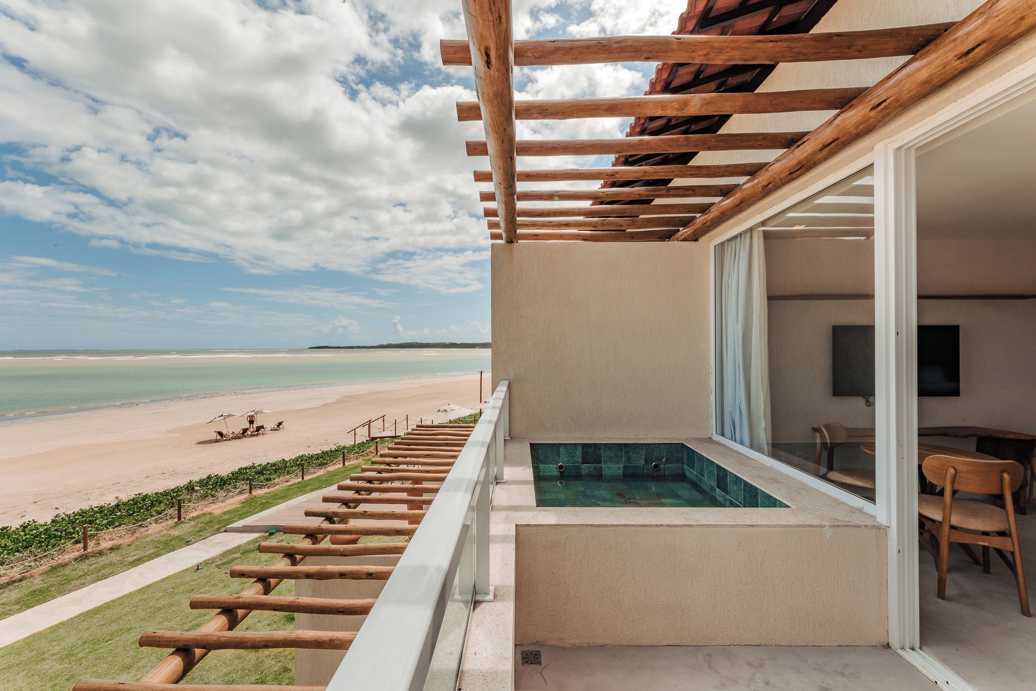 A balcony with a view of a beach and a pool.