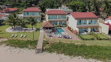 A resort with multiple buildings, a swimming pool, and a beach area with sun loungers.