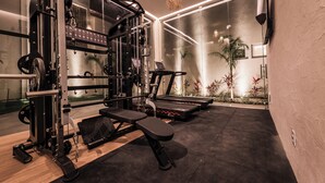 A modern gym with various exercise equipment, including a treadmill and weight machines. - Pousada Aysú (Japaratinga)