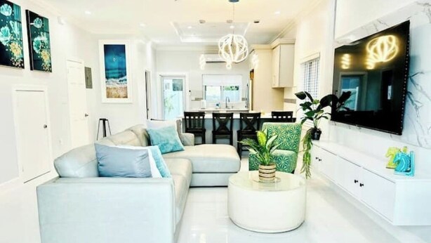 A modern living room with a sectional sofa, a round coffee table, and a TV mounted on the wall. - Private pool island retreat.

 (Nassau)