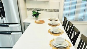 A dining table set with plates and bowls, a potted plant, and a modern kitchen with stainless steel appliances. - Private pool island retreat.

 (Nassau)