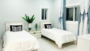 A bedroom with two beds, a window, and a nightstand with a plant. - Private pool island retreat.

 (Nassau)