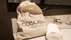 Une serviette blanche et un sac beige sur lequel on peut lire les mots « COSCAÑA » et « UYUNI HOTEL by Toloma », le tout posé sur le comptoir d’une salle de bain.