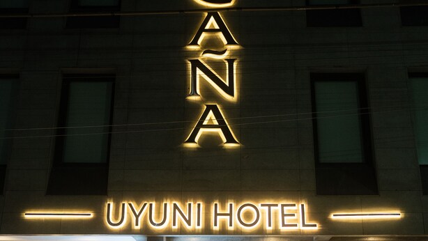 Une enseigne d’hôtel avec des lettres lumineuses épelant « COSCANA » et, en dessous, « UYUNI HOTEL ».