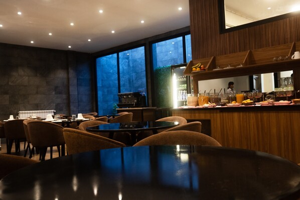 A restaurant with a bar area, tables, and chairs.