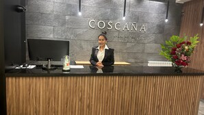 Un comptoir d’accueil avec un mur en pierre sombre, une enseigne indiquant « HÔTEL COSCANA UYUNI », et un décor mural en lambris de bois.