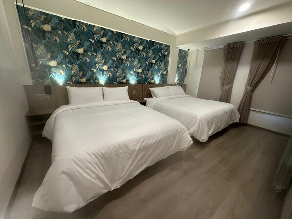 Une chambre d’hôtel avec deux lits, une tête de lit en bois, un papier peint à motifs floraux et une fenêtre avec des rideaux.