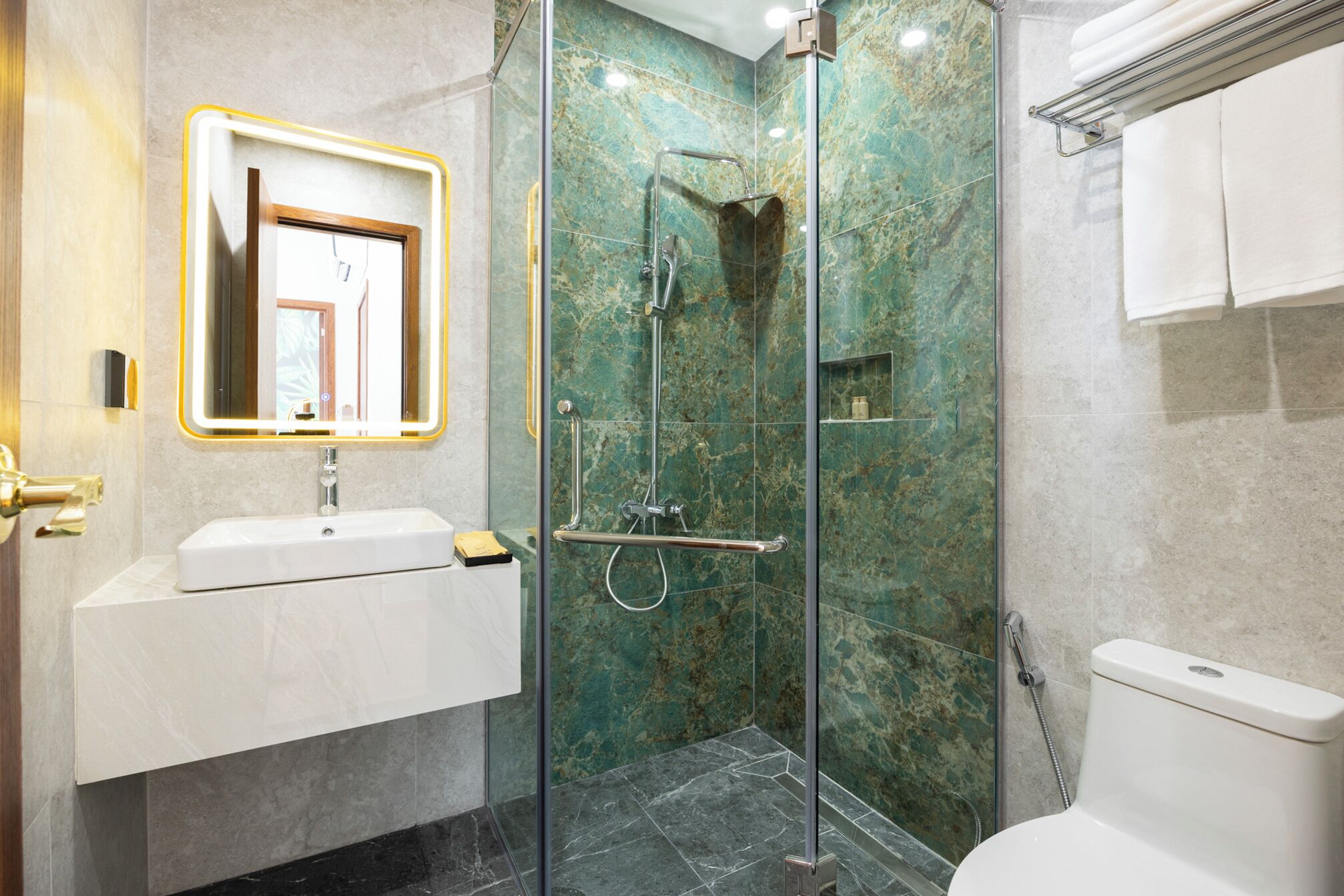 Un baño moderno con cabina de ducha de vidrio, un lavabo blanco y un inodoro.