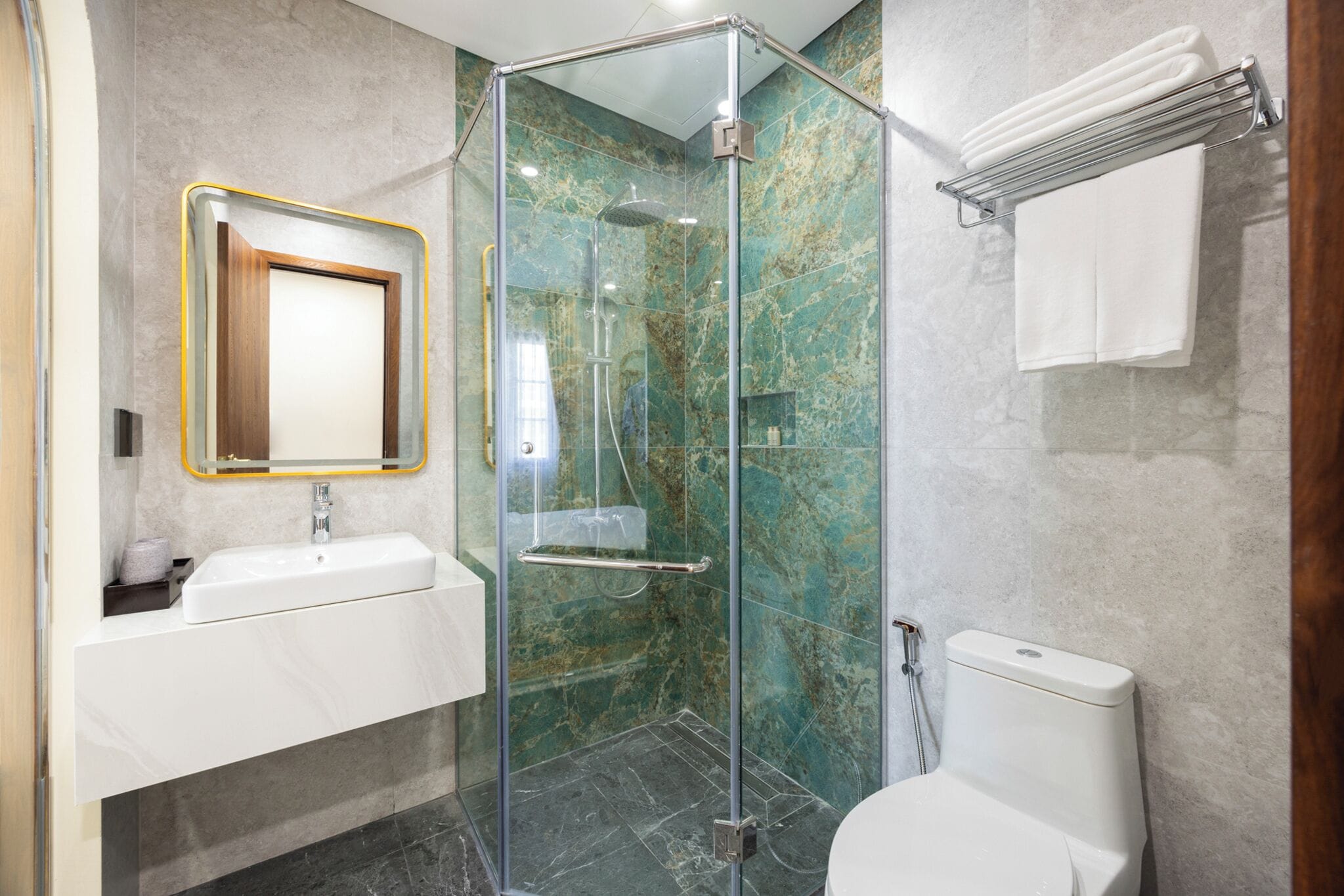 A modern bathroom with a glass-enclosed shower, a white sink, and a toilet.
