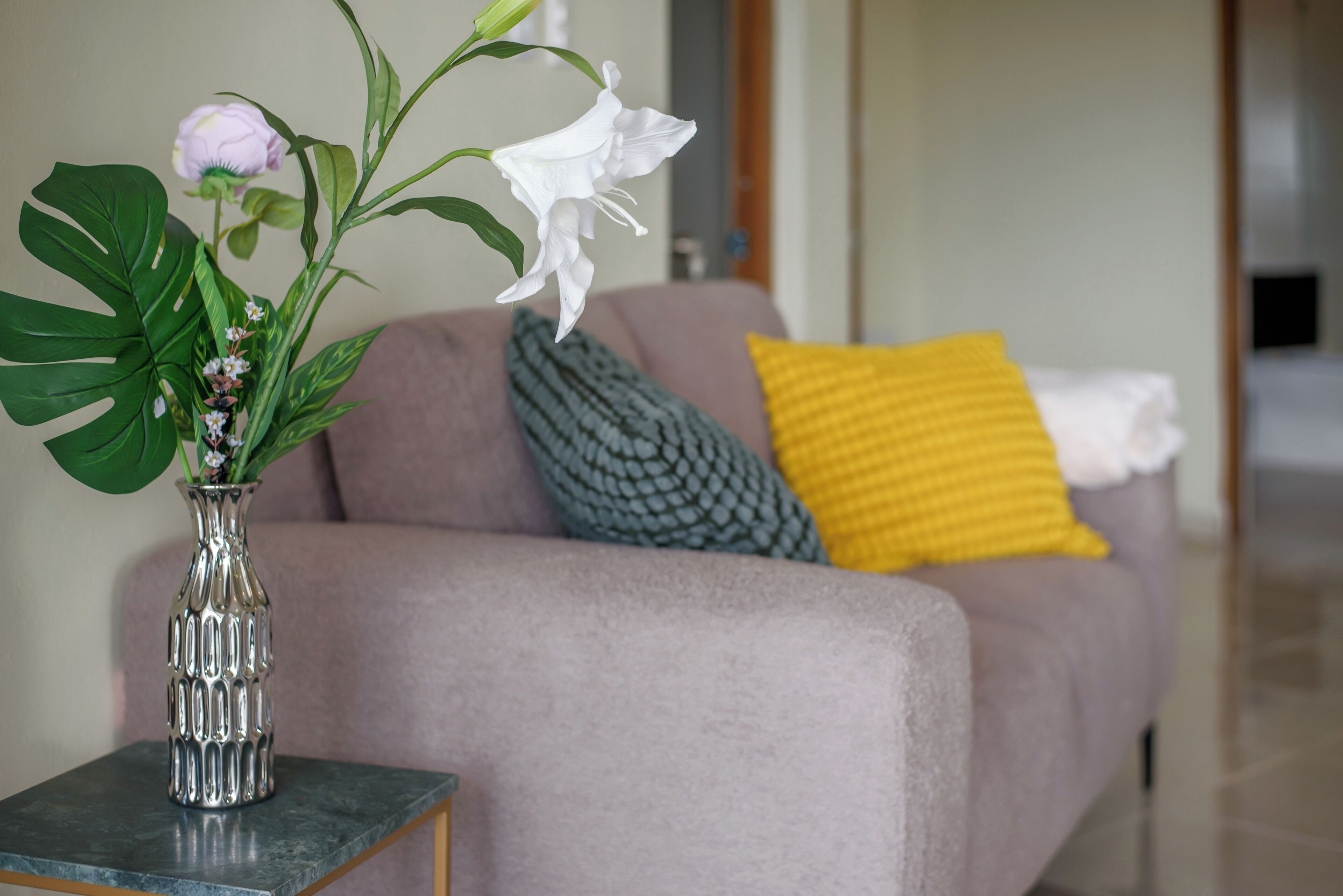 A living room with a sofa, a vase with flowers, and a small table.