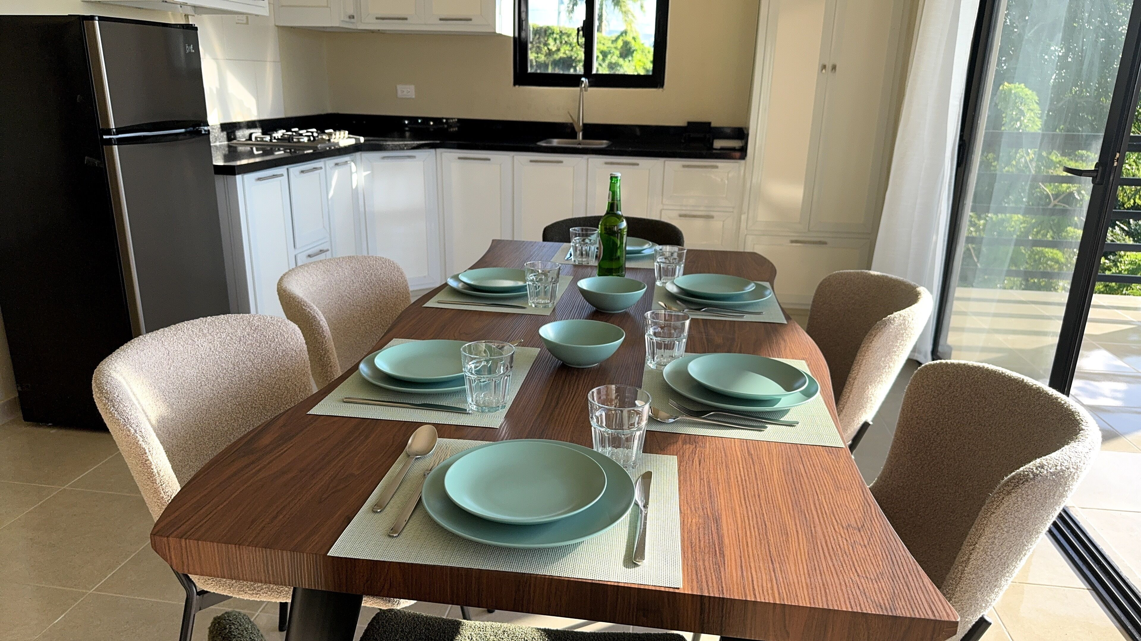 A dining area with a wooden table set for four, surrounded by chairs.