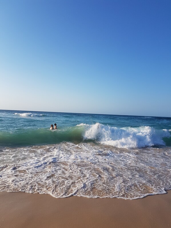 A beach with waves and two people in the water. - Casa Vista Mar 3 (Rio San Juan)