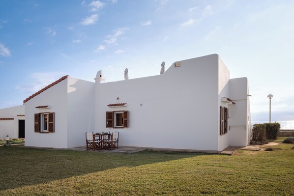 Un edificio blanco con un patio, una mesa y sillas.