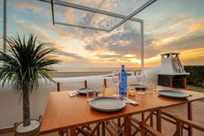 Mesa de comedor para dos con vista al océano al atardecer.
