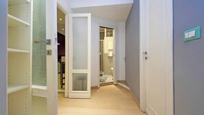 A hallway with a wooden floor, a white door with a frosted glass panel, and a light switch on the wall. - Trendy Flat near Marconi (Rome)