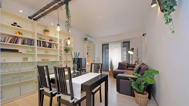 A modern living room with a dining area, featuring a sofa set, a dining table with chairs, and a bookshelf filled with books and decorative items. - Trendy Flat near Marconi (Rome)