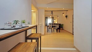A modern kitchen with a wooden countertop, a dining area with a table and chairs, and a hanging plant. - Trendy Flat near Marconi (Rome)