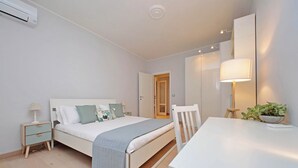 A bedroom with a bed, bedside table, lamp, and a potted plant. - Trendy Flat near Marconi (Rome)