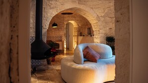 Ein gemütliches Interieur mit einem steinernen Bogen, einem modernen, geschwungenen Sofa und einem schwarzen Kamin.