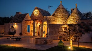 Un bâtiment en pierre, doté de toits coniques et d’une fenêtre circulaire, éclairé par une lumière chaleureuse.