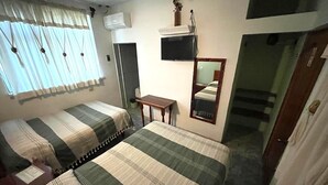 A room with two beds, a small table, a mirror, and a window with curtains. - Hotel Cosoleacaque Centro (Cosoleacaque)