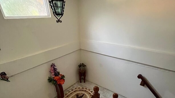 A staircase with a wooden handrail, a patterned rug, and a small table with a vase of flowers. - Hotel Cosoleacaque Centro (Cosoleacaque)