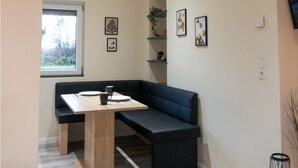 Une cuisine moderne dotée d’un banc intégré, d’une fenêtre et d’étagères murales ornées d’objets décoratifs.