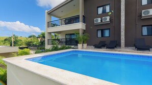 A modern building with a swimming pool, outdoor seating, and multiple balconies. - Casa Vista Mar 4 (Rio San Juan)