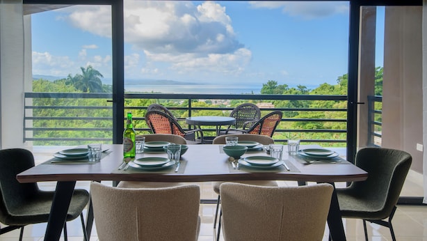 A dining area with a table set for four, overlooking a lush landscape with a view of the sea and mountains. - Casa Vista Mar 4 (Rio San Juan)