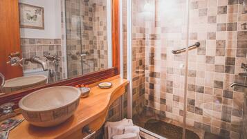 Ein Badezimmer mit Holzwaschtisch, einem großen Spiegel, einer Duschkabine aus Glas und einer gefliesten Duschwand.