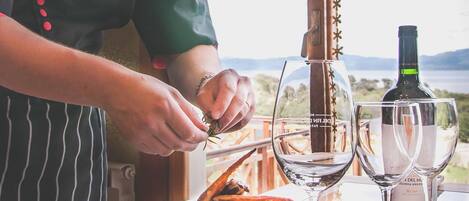 Un chef preparando comida sobre una mesa con una botella de vino y copas.