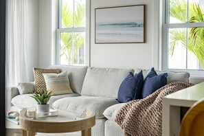 A cozy living room with a grey sofa, a small round table with a candle, and a framed picture on the wall. - Coral Reef Casa & Mistico Beach Club+Boat Shuttle (San Pedro)