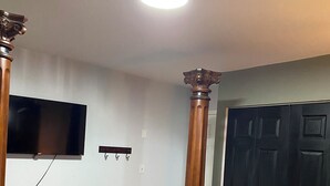 A bedroom with a bed, a television mounted on the wall, a wooden door, and a ceiling light. - Spacious 4 bedroom home walking distance from snowmobile and orv trails (Kincheloe)