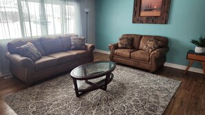 A living room with two brown leather sofas, a glass coffee table, and a patterned rug. - Spacious 4 bedroom home walking distance from snowmobile and orv trails (Kincheloe)