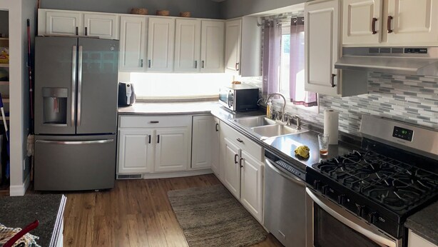 A modern kitchen with white cabinets, stainless steel appliances, a built-in oven, and a gas stove. - Spacious 4 bedroom home walking distance from snowmobile and orv trails (Kincheloe)