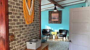 A room with a brick wall, a wooden bench, a white door, and a ceiling fan. - Spacious 4 bedroom home walking distance from snowmobile and orv trails (Kincheloe)