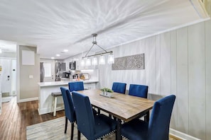 A modern dining area with a wooden table, blue chairs, and a pendant light fixture.