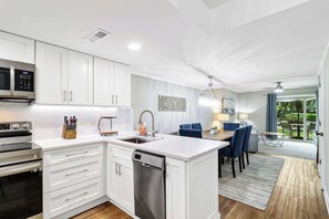 A modern kitchen with white cabinetry, a built-in dishwasher, and a microwave.