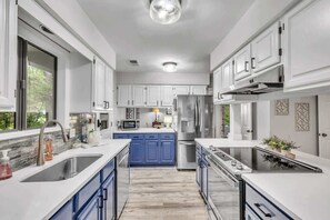 A modern kitchen with white cabinets, a stainless steel refrigerator, and a built-in oven.