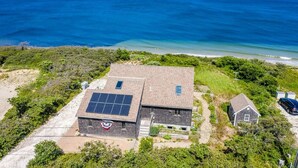 Un edificio con paneles solares, una pequeña construcción adyacente y vistas al océano.
