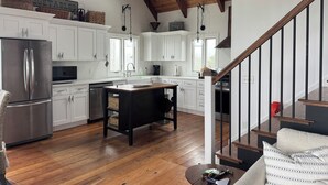 Una cocina amplia con armarios blancos, un refrigerador de acero inoxidable e una isla de madera.