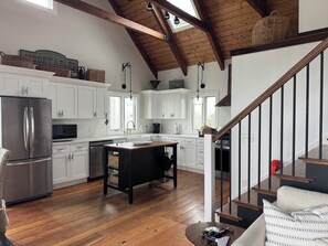 A spacious kitchen with white cabinets, a stainless steel refrigerator, and a wooden island. - Charming Handicapped Accessible 3-bedroom house in Welcoming Wellfleet (Wellfleet)