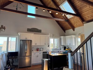 A spacious kitchen with white cabinets, a stainless steel refrigerator, and a wooden ceiling. - Charming Handicapped Accessible 3-bedroom house in Welcoming Wellfleet (Wellfleet)