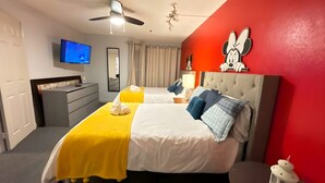 Ein Hotelzimmer mit Bett, Fernseher, Kommode und einer roten Akzentwand.