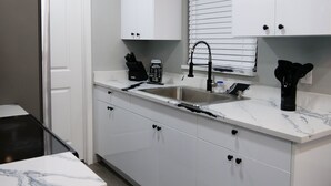 Una cocina moderna con armarios blancos, un lavamanos de acero inoxidable y un grifo negro.