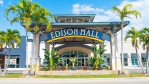 Exterior del centro comercial Edison, con entrada despejada, palmeras y un letrero azul y blanco.