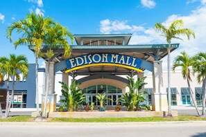 Exterior del centro comercial Edison, con entrada despejada, palmeras y un letrero azul y blanco.