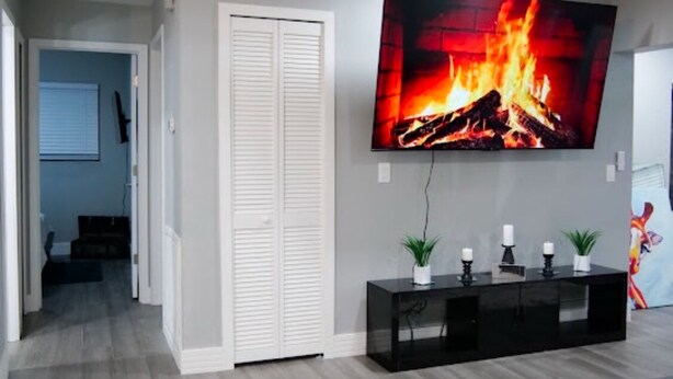 Una sala de estar con chimenea, televisor montado en la pared y mueble de entretenimiento negro.