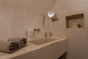 A bathroom with a sink, a mirror, a towel, and a shelf with toiletries. - Appartamento a Palazzo Coardi by Wonderful Italy (Turin)
